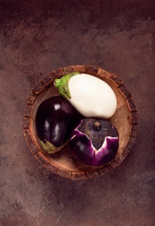 Colored eggplant, in a wooden bowl, white, purple and black eggplant, top view, raw eggplant, no