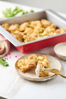 Baked cauliflower with spices and cheese, presented in a metal baking form. This vegetarian meal is