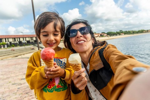 Happy mother and son taking a selfie together, holding ice cream cones while on vacation at the