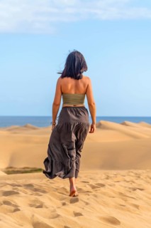 Woman walking barefoot on the sand enjoying the sunny day at maspalomas dunes in gran canaria