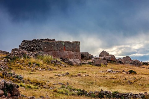 Stone construction on a hill under a dramatic dark sky, The Chullpas of Sillustani near Puno in