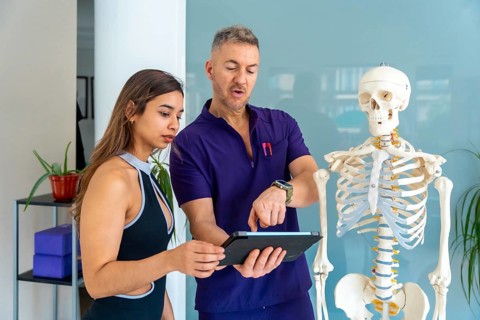 Physiotherapist consulting female patient about injury diagnosis and rehabilitation plan, using a