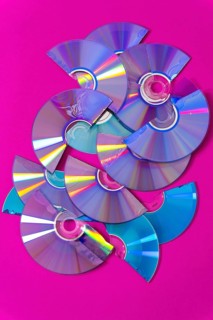 Top view of cut CDs and DVDs against a magenta background