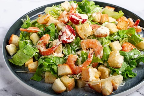 Caesar salad, with shrimp, on a marble background, top view, no people