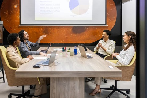 A diverse team collaborates in a modern office setting. They're engaged in a lively discussion
