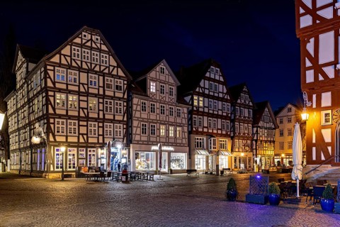 Illuminated half-timbered houses in a cobbled street at night, The old town centre of Melsungen