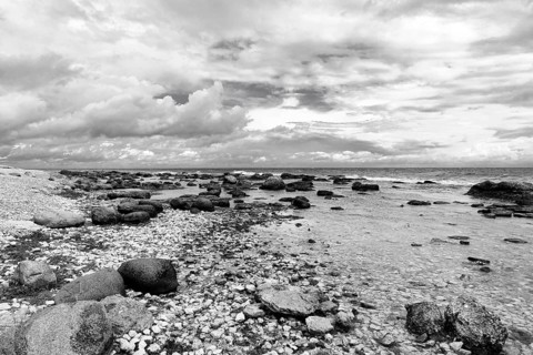 Characteristic coastline, wild natural beach, boulders, dramatic cloudy sky, monochrome, film set,