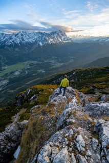 View of Wetterstein mountains with Zugspitze, mountaineer at the summit of Kramerspitz, at sunset,