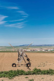 A center pivot irrigation system stands on freshly plowed farmland in Toledo, Spain. The rural
