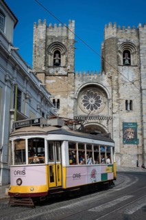 LISBON, PORTUGAL - MAY 19, 2025: Famous tram number 28 at the street and cathedral Se in the