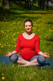 Pregnancy yoga exercise, pregnant woman doing asana Sukhasana easy yoga pose with chin mudra