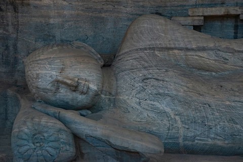 Close-up view of an ancient stone carving depicting the serene face of a reclining Buddha. Located