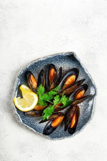 Mussels in shells, boiled in their own juice, in a bowl, gray background, top view, homemade, no