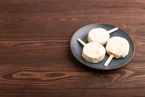 ?hocolate Ice cream in white glaze, on brown wooden background, side view, copy space