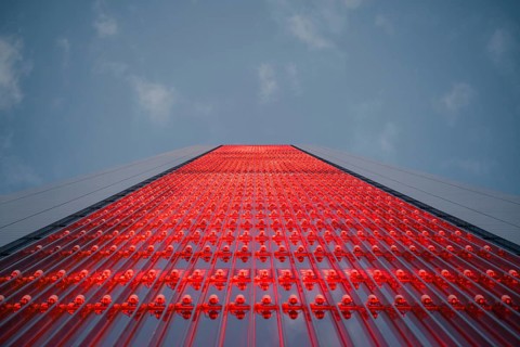 A striking close-up of a downtown skyscraper adorned with vibrant red lights, capturing the essence