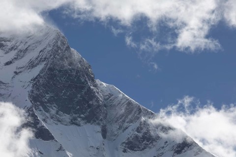 A breathtaking view of Mount Everest's towering, snow-covered peak piercing through the clouds