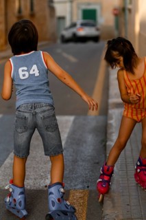 Kids enjoy a sunny day rollerblading on a quiet street in Santa Maria del Cami, Mallorca. The scene