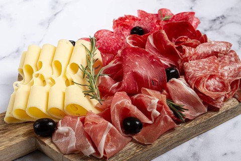 Assorted meat, appetizer, prosciutto, salami and ham, with maasdam cheese and olives, on a wooden