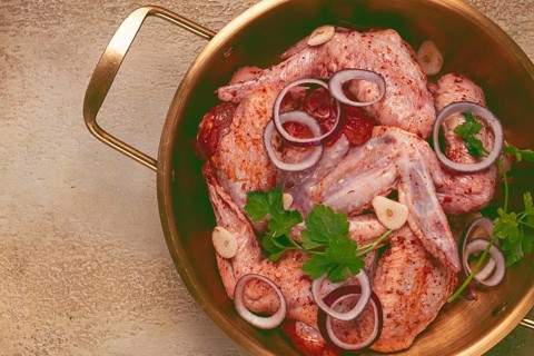 Chicken wings, in a brass saucepan, ready for cooking, grilling or baking, in a home kitchen, no