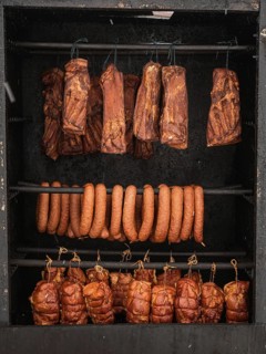 Cooked meats: bacon, ham and sausage hanging in the smoker