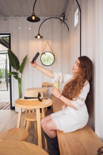 A young Latin American woman enjoying a casual moment in a stylish cafe. She captures a selfie