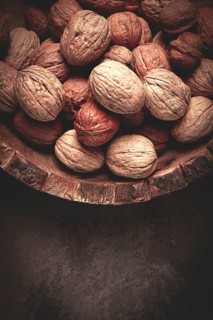 Fresh walnut in a shell, wooden plate, top view, no people