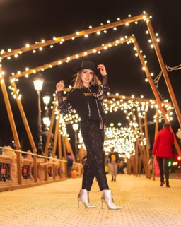 Christmas lights in the city, Caucasian blonde girl dressed in black and with sequins walking on an