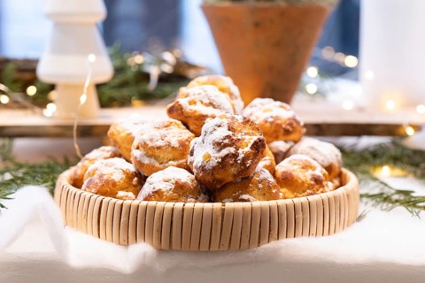 A basket filled with delicious pastries dusted with powdered sugar, set on a festive holiday table.