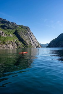 Kayaker with red kayak in the fjord Trollfjord, mountain peaks reflected in the water, fjord
