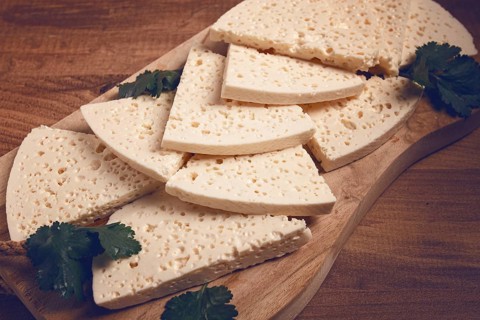 Sliced Georgian cheese, factory grade, on a wooden board, top view