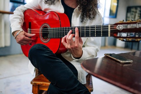 Anonymous Latin man playing red bass guitar in studio