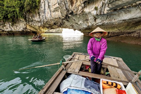 Guided boat under a huge rock cave, rowing boats for tourists in Halong Bay in Vietnam