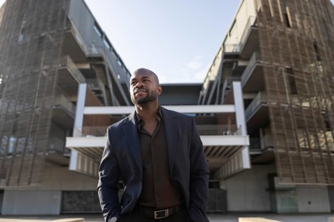 A business cuban man in a suit stands confidently outside a modern office building, exuding