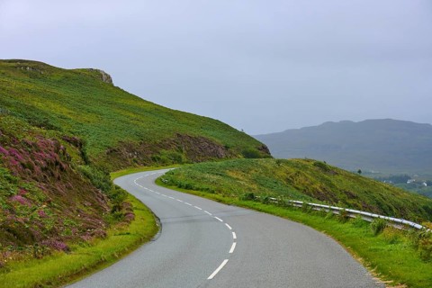 Curved road through rolling green vegetation under overcast sky, Isle of Skye, Scotland, United
