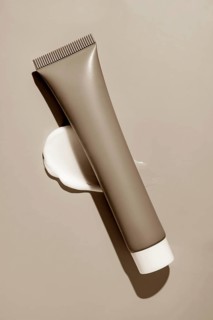 A sleek cosmetics package with creamy smears elegantly displayed on a serene background, showcasing