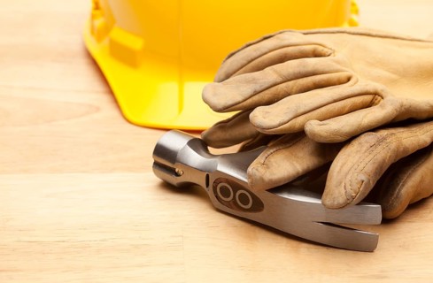 Yellow Hard Hat, Gloves and Hammer on Wood Surface