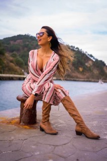 Portrait of a young Latin woman in a pink dress, brown boots and sunglasses enjoying summer