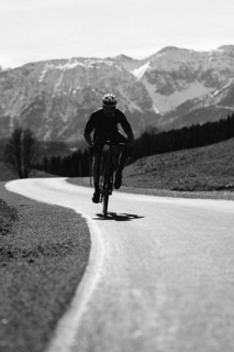Road bike rider in spring in the Allgäu against the picturesque backdrop of the Alps, Bavaria,
