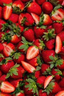 From above, a vibrant array of fresh strawberries showcases their rich red hues with green leaves,