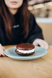 A tantalizing chocolate whoopie pie with creamy filling rests on a light blue plate, tempting taste