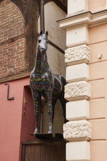 Horse sculpture with colourful lettering looks between a narrow passage between two buildings in