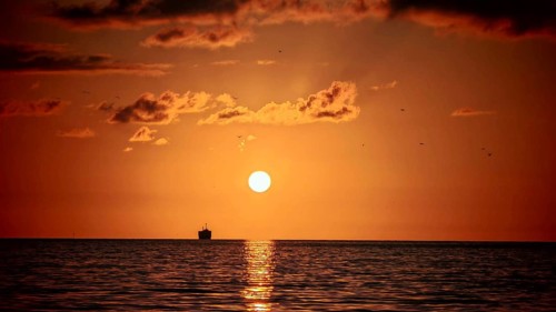 Romantic sunset over the sea with a ship on the horizon and orange sky, Batumi, Georgia