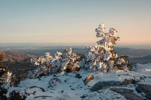 A breathtaking view of Siete Picos in Guadarrama Mountains, Madrid, covered in snow. The sun casts