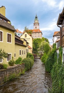 View of Ceský Krumlov Castle tower from a street with buildings and a stream, Cesky Krumlov, Czech