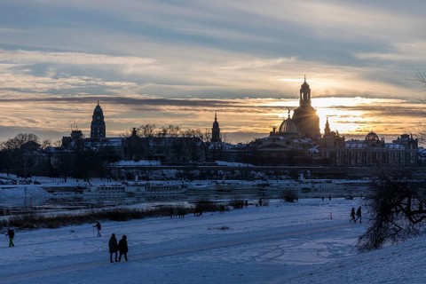 City view with Elbe, Town Hall Tower and Church of Our Lady dome in snow at sunset, Dresden,