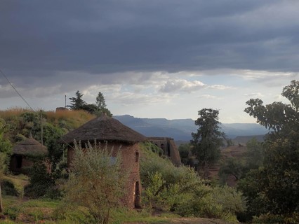 Evening atmosphere over a village with traditional round huts, clay huts with thatched roofs and a