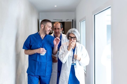 Healthcare professionals, including a female doctor and two male colleagues, discussing patient