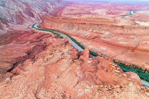 Stunning aerial shot of the Rio San Juan curving through the deeply eroded, colorful red rock
