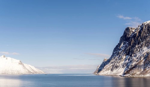 A breathtaking view of the snow-covered mountains and calm waters of the fjord in Mefjordbotn,