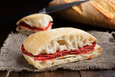 A delicious homemade chorizo sandwich layered with slices of melting cheese, served on a crusty